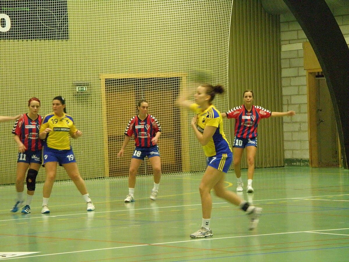 Women's handball action — player throwing toward goal